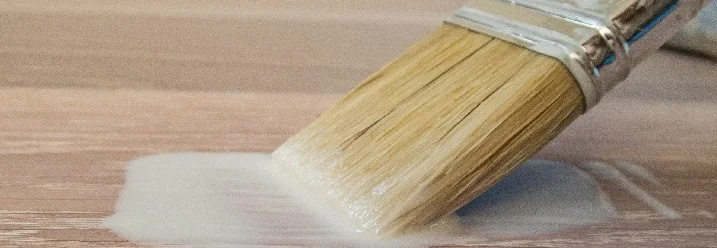 Pinsel trägt weiße Farbe auf Holz auf